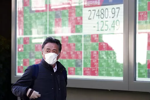 A person walks in front of an electronic stock board showing Japan's Nikkei 225 index at a securities firm Thursday, Feb. 9, 2023, in Tokyo. Shares fell Thursday in Asia after Wall Street gave back some of its recent gains on persisting uncertainty over interest rates and inflation. (AP Photo/Eugene Hoshiko)