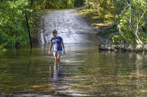 Teresa Elder walks through a flooded Sandy Cove Drive from Hurricane Helene, Sept. 27, 2024, in Morganton, N.C. (AP Photo/Kathy Kmonicek, File)