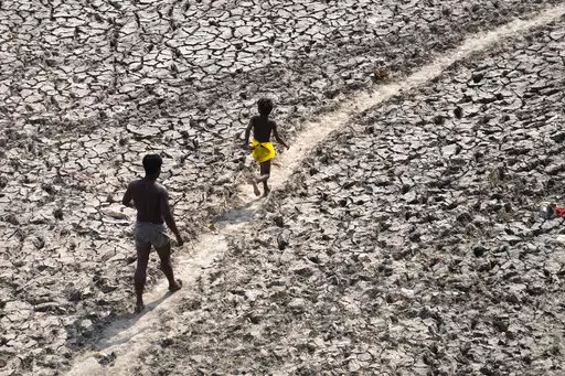 A man and a boy walk across the almost dried up bed of river Yamuna following hot weather in New Delhi, India, Monday, May 2, 2022. According to a report released by the World Meteorological Organization on Monday, May 9, 2022, the world is creeping closer to the warming threshold international agreements are trying to prevent, with nearly a 50-50 chance that Earth will temporarily hit that temperature mark within the next five years. (AP Photo/Manish Swarup, File)