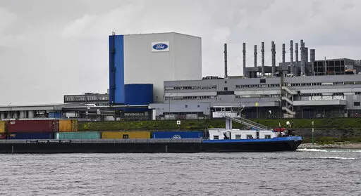 A container ship passes the Ford car plant in Cologne, Germany, May 4, 2020. Ford said that it will cut 3,800 jobs in Europe over the next three years in an effort to streamline its operations as it contends with economic headwinds and increasing competition on electric cars. The automaker said that 2,300 jobs will go in Germany. (AP Photo/Martin Meissner, File)