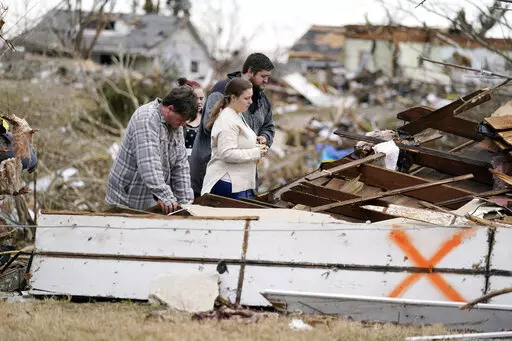 FILE -Brandon Clark, behind, injured from the tornado, returns to his destroyed home for the first time with Laura Shepherd, Tyler Shepherd, left, and his wife Georgialee Clark, behind in the aftermath of tornadoes that tore through the region, in Dawson Springs, Ky., Wednesday, Dec. 15, 2021. One year ago Saturday, Dec. 10, 2022, a massive tornado obliterated wide swaths of Dawson Springs, Ky. (AP Photo/Gerald Herbert, File)