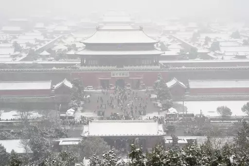 The snow covered Forbidden City is seen from a hilltop pavilion in Beijing, Wednesday, Dec. 13, 2023. Throngs of people in boots and down parkas climbed a hill that overlooks the Forbidden City this week to jostle with others trying to get a shot of the snow-covered roofs of the former imperial palace. (AP Photo/Ng Han Guan)