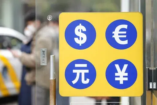 People walk near a sign of foreign currency outside a money exchange office at a shopping district in Seoul, South Korea, Tuesday, Feb. 28, 2023. Shares climbed in Asia on Tuesday after Wall Street benchmarks clawed back some losses from their worst week since early December.(AP Photo/Lee Jin-man)