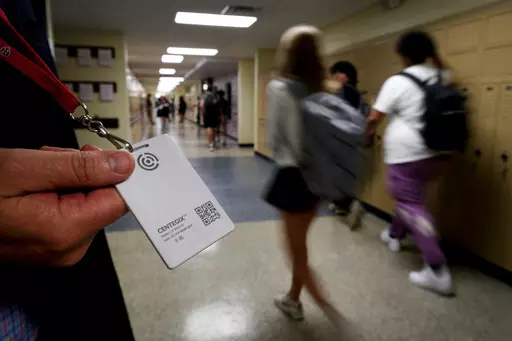 Brent Kiger, Olathe Public Schools' director of safety service, displays a panic-alert button while students at Olathe South High School rush between classes, Aug. 19, 2022, in Olathe, Kan. The district introduced the buttons, which allow staff to trigger a lockdown that will be announced with flashing strobe lights, a takeover of staff computers and a prerecorded intercom announcement, at the start of this school year as part of $2.1 million plan to make district schools more secure. In the wak