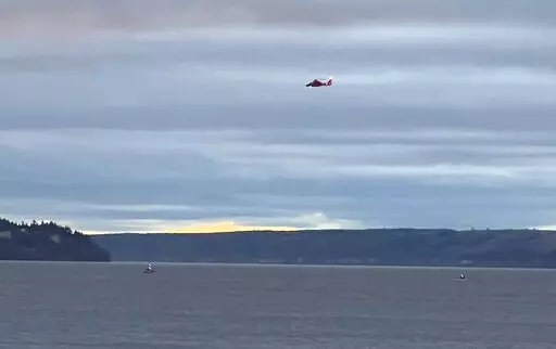 A Coast Guard helicopter searches the area where a floatplane crashed near Whidbey Island, Wash., Sunday, Sept. 4, 2022. (Courtney Riffkin/The Seattle Times via AP)