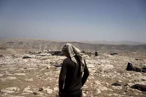 Palestinian shepherd Mustafa Arara, 24, stands in the ruins of the West Bank Bedouin village of al-Baqa where residents fled in July after settlers established an outpost a stone's throw from the village in June, Wednesday, Aug. 9, 2023. Out of 33 people who fled the Palestinian hamlet east of Ramallah, just one six-person family has returned after settlers from a newly established outpost wreaked havoc on the village, setting their sheep loose on Palestinian grazing fields and torching a home. 