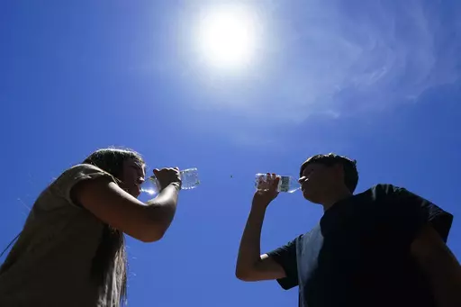 Tony Berastegui Jr., right, and his sister Giselle Berastegui drink water, Monday, July 17, 2023, in Phoenix. A historic heat wave that turned the Southwest into a blast furnace throughout July is beginning to abate with the late arrival of the monsoon rains. Forecasters expect that by Monday, July 31, at the latest, people in metro Phoenix will begin seeing high temperatures under 110 degrees Fahrenheit (43.3 degrees Celsius) for the first time in a month. (AP Photo/Ross D. Franklin, File)