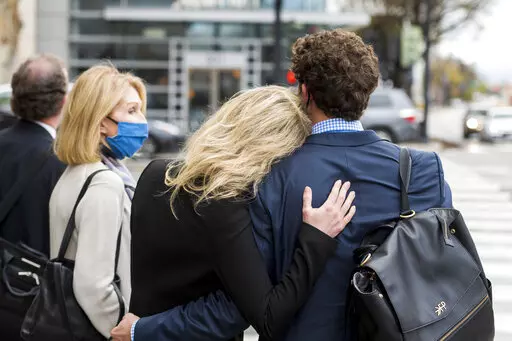 Former Theranos CEO Elizabeth Holmes, center, is comforted by her partner Billy Evans, right, after leaving federal court in San Jose, Calif., Thursday, Dec. 23, 2021. Her mother, Noel Holmes, is on the left, The jury began their third day of deliberations in her fraud and conspiracy trial on Thursday. (AP Photo/Nic Coury)