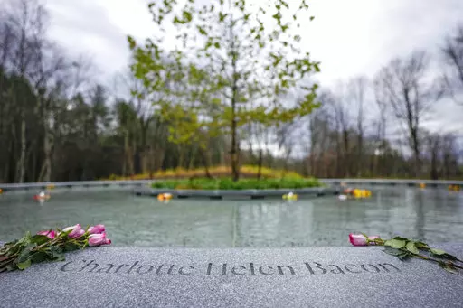 Flowers lay next to the name of Charlotte Bacon, carved in the stone of a memorial dedicated to the victims of the Sandy Hook Elementary School shooting, in Newtown, Conn., Sunday, Nov. 13, 2022. (AP Photo/Bryan Woolston)