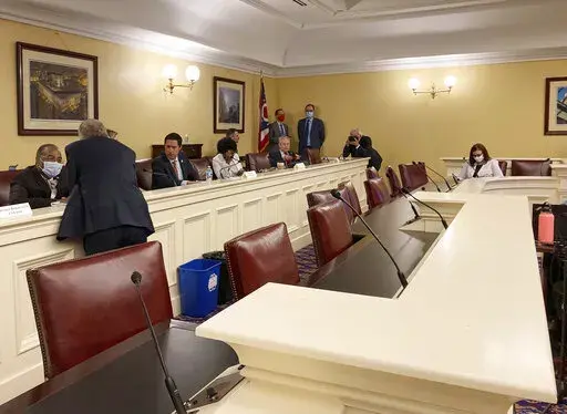 In this Sept. 15, 2021, photo, Republican Ohio Gov. Mike DeWine, foreground, speaks to state Sen. Vernon Sykes, seated, the co-chair of the Ohio Redistricting Commission, as other members of the panel prepare for a meeting on at the Ohio Statehouse in Columbus, Ohio. The GOP's focus on the makeup of state supreme courts escalated this week after a series of legal setbacks frustrated the party's effort to redraw congressional maps in Pennsylvania and North Carolina. That prompted some leading Rep