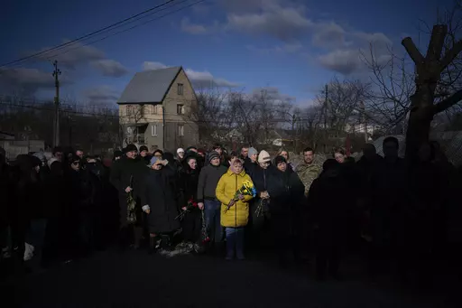 People pay respect as the coffin containing the body of Serhii Havryliuk, 48, passes by during his funeral procession in Tarasivka village, near Kyiv, Ukraine, Wednesday, Feb. 15, 2023. Serhii Havryliuk, an officer of the Azov Assault Brigade, died while defending the Azovstal steel plant in Mariupol on April 12, 2022 against the Russians. Serhii has finally been buried after DNA tests confirmed his identity. (AP Photo/Emilio Morenatti, File)