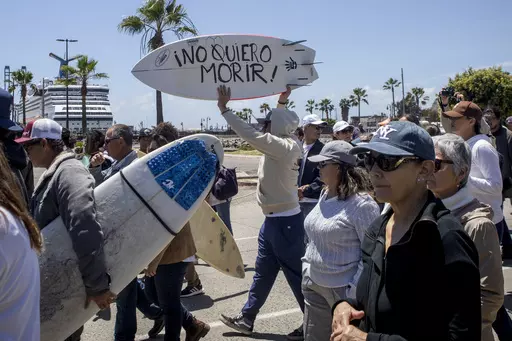 A demonstrator holding a bodyboard written in Spanish " I don't want to die" protests the disappearance of foreign surfers in Ensenada, Mexico, Sunday, May 5, 2024. Mexican authorities said Friday that three bodies were recovered in an area of Baja California near where two Australians and an American went missing last weekend during an apparent camping and surfing trip. (AP Photo/Karen Castaneda)