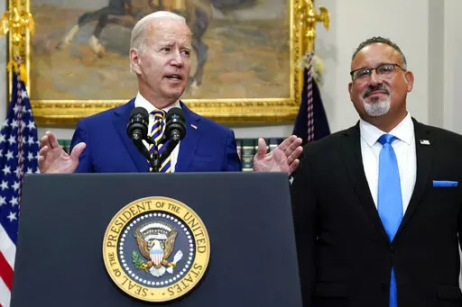FILE — President Joe Biden speaks about student loan debt forgiveness in the Roosevelt Room of the White House, Aug. 24, 2022, in Washington. Education Secretary Miguel Cardona listens at right. Many have cheered President Joe Biden's proposal to provide student loan forgiveness to millions of Americans as a significant step toward addressing the nation's racial wealth gap and other inequities facing borrowers of color. (AP Photo/Evan Vucci, File)