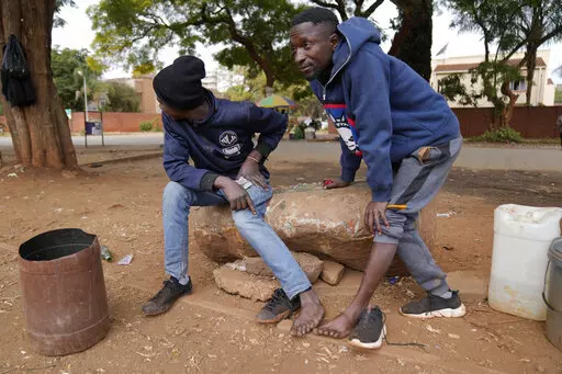 Street vendors take off their shoes to show their toes on the streets of Harare, Zimbabwe, Thursday, June, 9, 2022. Rampant inflation is making it increasingly difficult for people in Zimbabwe to make ends meet. Since the start of Russia’s war in Ukraine, official statistics show that Zimbabwe’s inflation rate has shot up from 66% to more than 130%. The country's finance minister says the impact of the Ukraine war is heaping problems on the already fragile economy. (AP Photo/Tsvangirayi Mukw