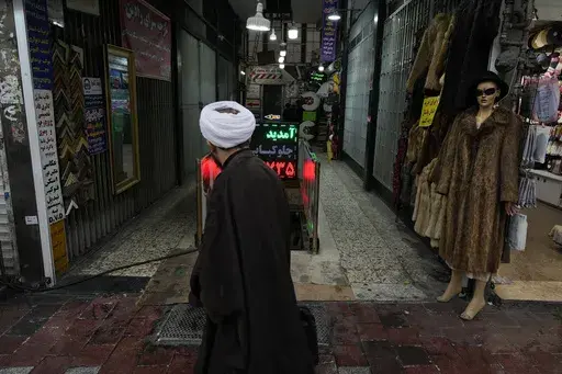 A cleric walks in front of a shopping center in northern Tehran, Iran, Monday, Jan. 27, 2025. (AP Photo/Vahid Salemi)