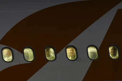 Venezuelan migrants deported from the United States peer through their plane window as they arrive at Simon Bolivar International Airport in Maiquetia, Venezuela, Monday, March 24, 2025. (AP Photo/Ariana Cubillos)
