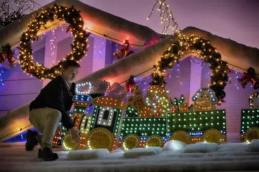 Resident Bryan Cobb puts the finishing touches on the lights on his house for the Wakefield Winter Wonderland lighted street in Santa Clarita, Calif. on Dec. 17, 2024. (AP Photo/Richard Vogel)