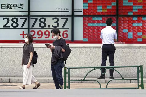 People wearing protective masks stand in front of an electronic stock board showing Japan's Nikkei 225 index at a securities firm Friday, Aug. 26, 2022, in Tokyo. Asian stock markets followed Wall Street higher on Friday ahead of speech by the Federal Reserve chair that investors hoped would shed light on plans for more interest rate hikes. (AP Photo/Eugene Hoshiko)