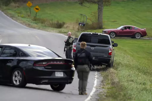 Law enforcement officers hold rifles while investigating a scene, in Bowdoin, Maine, Thursday, Oct. 26, 2023. On Friday, Oct. 27, The Associated Press reported on stories circulating online incorrectly claiming an aerial video of a man lying on his stomach in the middle of a road, being detained by authorities, shows police arresting Maine shooting suspect Robert Card. (AP Photo/Steven Senne, File)