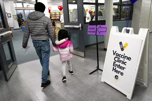 An information sign is displayed as a child arrives with her parent to receive the Pfizer COVID-19 vaccine for children 5 to 11-years-old at London Middle School in Wheeling, Ill., Wednesday, Nov. 17, 2021. (AP Photo/Nam Y. Huh)