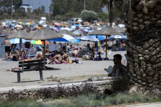 A man reads his book in the shadows of a tree at a beach, at Glyfada suburb, in Athens, Greece, Saturday, July 15, 2023. Greece's Finance Minister promised Wednesday, Aug. 2, 2023, to intensify inspections of beach bars and other businesses renting out seaside chaise lounges and umbrellas, following complaints that non-paying island beachgoers can't find a spot on the sand. (AP Photo/Yorgos Karahalis, File)