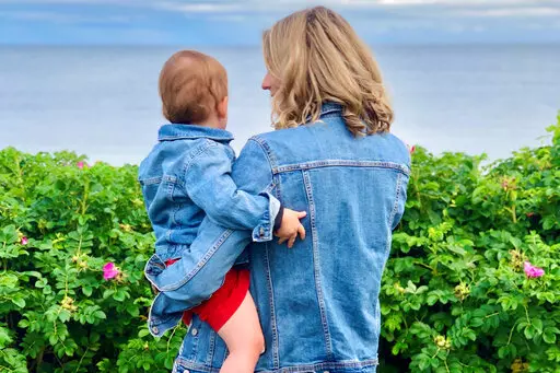 This photo provided by Alex Richer shows his wife, AP writer Alanna Durkin Richer, holding one of their children at Massachusetts' Cape Cod on July 4, 2021. In the aftermath of the May 2022 Uvalde, Texas, school shooting, she writes, "I know rationally that I can’t keep my almost 3-year-old son and his 7-month-old sister in a bubble all their lives. No matter how hard I try, I won't always be able to protect them from harm and pain. But why should I have to fear simply sending them to school?"