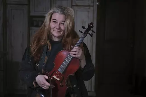 Oksana, 49, who did not want her surname reported, shows a violin she made herself in her small and cold apartment in Bakovka, on the outskirts of Moscow, Russia, Tuesday, Feb. 8, 2022.Oksana's music and colorful instruments lift the spirits of Moscow commuters whose rides are often uncomfortable. (AP Photo/Vitaly Zhiryakov)