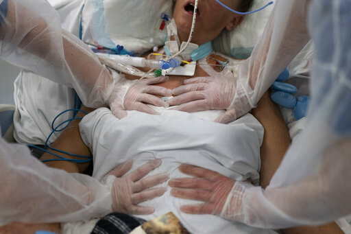 Nurses perform timed breathing exercises on a COVID-19 patient on a ventilator in the COVID-19 intensive care unit at the la Timone hospital in Marseille, southern France, Friday, Dec. 31, 2021. The official global death toll from COVID-19 is on the verge of eclipsing 6 million — underscoring that the pandemic, now in its third year, is far from over. (AP Photo/Daniel Cole, File)