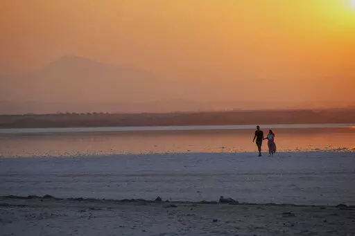 A couple walk at the salt lake during sunset in southeast coastal city of Larnaca in southeast Mediterranean island of Cyprus, on Sept. 5, 2022. The eastern Mediterranean and Middle East are warming almost twice as fast as the global average, with temperatures projected to rise up to 5 degrees Celsius (9 degrees Fahrenheit) by the end of the century if no action is taken to reverse the trend, a new report says. (AP Photo/Petros Karadjias, File)