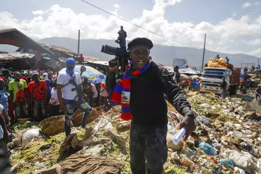 Barbecue, the leader of the "G9 and Family" gang, stands next to garbage to call attention to the conditions people live in as he leads a march against kidnapping through La Saline neighborhood in Port-au-Prince, Haiti, Friday, Oct. 22, 2021. Haiti Prime Minister Ariel Henry and 18 top-ranking officials have requested on the second week of Oct. 2022, the immediate deployment of foreign armed troops as gangs and protesters paralyze the country. (AP Photo/Odelyn Joseph, File)