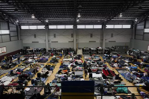 Ukrainian refugees wait in a gymnasium Tuesday, April 5, 2022, in Tijuana, Mexico. As many as 20,000 Ukrainians who were granted permission to remain in the United States for one year after fleeing the early fighting in their native country are facing their humanitarian parole expiring, according to advocates. (AP Photo/Gregory Bull, File)