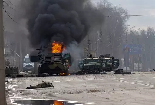 A Russian armored personnel carrier burns amid damaged and abandoned light utility vehicles after fighting in Kharkiv, the country's second-largest city in Ukraine, Feb. 27, 2022. Three months after it invaded Ukraine hoping to overtake the country in a blitz, Russia has bogged down in what increasingly looks like a war of attrition with no end in sight. (AP Photo/Marienko Andrew, File)