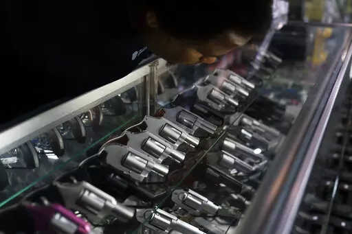 Sales associate Elsworth Andrews arranges guns on display at Burbank Ammo & Guns in Burbank, Calif., Thursday, June 23, 2022. The Supreme Court has ruled that Americans have a right to carry firearms in public for self-defense, a major expansion of gun rights. The court struck down a New York gun law in a ruling expected to directly impact half a dozen other populous states. (AP Photo/Jae C. Hong)