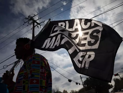 In this Dec. 12, 2020, file photo, MD Crawford carries a Black Lives Matter flag before a march in La Marque, Texas to protest the shooting of Joshua Feast, 22, by a La Marque police officer. The Black Lives Matter Global Network Foundation launched a new relief fund Monday, Dec. 12, 2022 aimed at Black college students, alumni and dropouts overburdened by mounting education costs and the student loan debt crisis. (Stuart Villanueva /The Galveston County Daily News via AP, File)