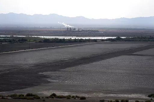 A dried up portion of the Salton Sea stretches out with a geothermal power plant in the distance in Niland, Calif., Thursday, July 15, 2021. Demand for electric vehicles has shifted investments into high gear to extract lithium from geothermal wastewater around the rapidly shrinking body of water. The ultralight metal is critical to rechargeable batteries. (AP Photo/Marcio Jose Sanchez, File)