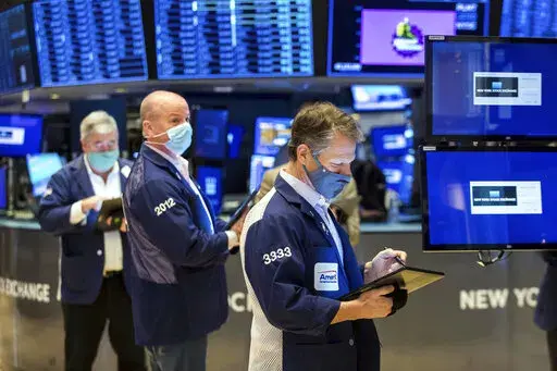 In this photo provided by the New York Stock Exchange, Robert Charmak, right, works with fellow traders on the floor of the New York Stock Exchange, Monday, Jan. 10, 2022. Stocks fell broadly in afternoon trading on Wall Street Monday and bond yields continued rising as investors anticipate moves by the Federal Reserve to raise interest rates. (Courtney Crow/New York Stock Exchange via AP)