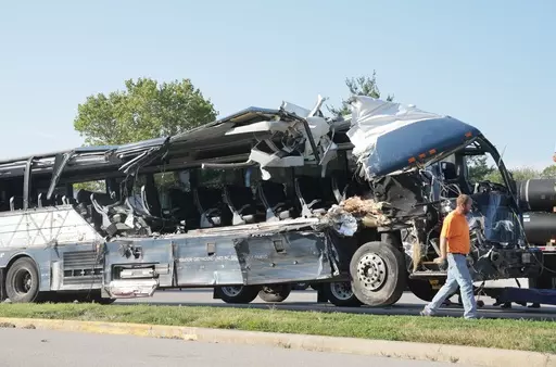 A worker helps clear the wreckage of a Greyhound bus that collided with tractor-trailers on the exit ramp to a rest area on westbound Interstate 70 in Highland, Ill., on Wednesday, July 12, 2023. (Christian Gooden/St. Louis Post-Dispatch via AP)
