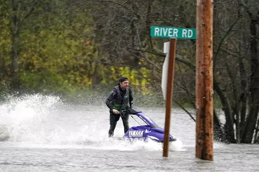 A man operates a personal watercraft along a road flooded by water from the Skagit River, Monday, Nov. 15, 2021, in Sedro-Woolley, Wash. (AP Photo/Elaine Thompson)