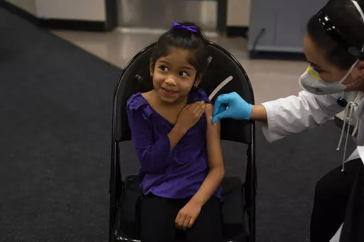 Elsa Estrada, 6, smiles at her mother as pharmacist Sylvia Uong applies an alcohol swab to her arm before administering the Pfizer COVID-19 vaccine at a pediatric vaccine clinic for children ages 5 to 11 set up at Willard Intermediate School in Santa Ana, Calif., Nov. 9, 2021. As of Tuesday, Jan. 11, 2022, just over 17% of children in the U.S. ages 5 to 11 were fully vaccinated, more than two months after shots for them became available. (AP Photo/Jae C. Hong, File)