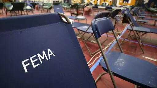 A portable cot, with the Federal Emergency Management Agency logo FEMA printed on the backrest, and other cots line the basketball court at a makeshift medical facility in a gymnasium at Southern New Hampshire University in Manchester, N.H., March 24, 2020. FEMA may have been double-billed for the funerals of hundreds of people who died of COVID-19, the Government Accountability Office said in a new report Wednesday, April 27, 2022. (AP Photo/Charles Krupa, File)