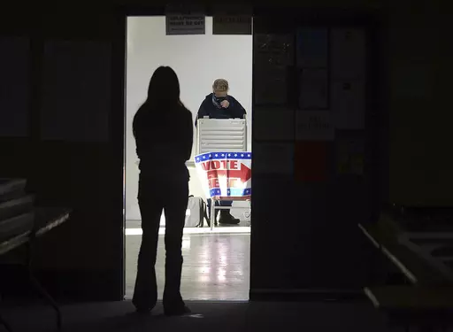 A first-time voter waits in the doorway for a voting booth as another voter completes his ballot at the Boot City Opry near Terre Haute, Ind., Nov. 3, 2020. (Joseph C. Garza/The Tribune-Star via AP, File)