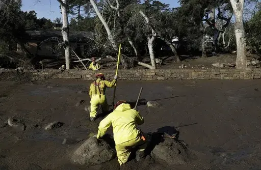 A Cal Fire search and rescue crew walks through mud near homes damaged by storms in Montecito, Calif., Jan. 12, 2018. (AP Photo/Marcio Jose Sanchez, File)
