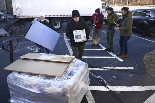 Andy Thibault, Editor and Publisher of The Winsted Citizen, carries the first bundle of papers off a pallet as Advertising and Circulation Director Rosemary Scanlon holds the first print press plate while a group of musicians play behind them after the arrival of the first delivery of the paper on, Friday, Feb. 3, 2023, in Winsted, Conn. At a time that local newspapers are dying at an alarming rate, longtime activist Ralph Nader is helping give birth to one. Nader put up $15,000 to help launch T