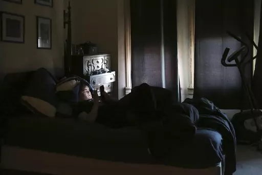 James Walter uses a phone at home in the Queens borough of New York, on April 7, 2021. Sleep scientists long ago established that insufficient sleep is linked with poor health outcomes, anxiety, obesity and several other negative effects. The research is equally conclusive that smartphones are particularly disruptive to the circadian clock that regulates sleep and other hormones. (AP Photo/Jessie Wardarski, File)