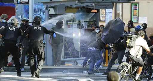 In this July 25, 2020, file photo, police pepper spray protesters, near Seattle Central College in Seattle, during a march and protest in support of Black Lives Matter.    Democratic lawmakers in California, Maryland and Washington passed far-reaching policing reforms this year in response to the 2020 killing of George Floyd in Minnesota. But the first full year of state legislative sessions since the killing sparked a summer of racial justice protests produced a far more mixed response in the r