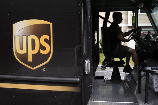 United Parcel Service driver Hudson de Almeida steers through a neighborhood while delivering packages, Friday, June 30, 2023, in Haverhill, Mass. UPS has reached a contract agreement with its 340,000-person strong union Tuesday, July 25, averting a strike that had the potential to disrupt logistics nationwide for businesses and households alike. (AP Photo/Charles Krupa, File)