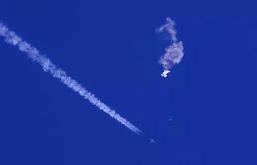 A fighter jet flies past the remnants of a large balloon after it was shot down above the Atlantic Ocean, just off the coast of South Carolina near Myrtle Beach, Feb. 4, 2023. The missile fired by a U.S. F-22 ended the days-long flight of what the Biden administration says was a surveillance operation that took the Chinese balloon near U.S. military sites. It was an unprecedented incursion across U.S. territory for recent decades, and raised concerns among Americans about a possible escalation i