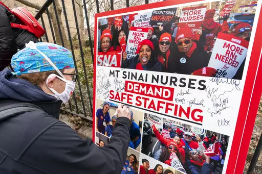 Zach Clapp, a nurse in the Pediatric Cardiac ICU at Mount Sinai Hospital signs a board demanding safe staffing during a rally by NYSNA nurses from NY Presbyterian and Mount Sinai, Tuesday, March 16, 2021, in New York. Negotiations to keep 10,000 New York City nurses from walking off the job headed Friday, Jna. 6, 2023, into a final weekend as some major hospitals braced for a potential strike by sending ambulances elsewhere and transferring such patients as vulnerable newborns. (AP Photo/Mary Al