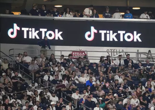 Fans sit under a TikTok ad at a baseball game at Yankee Stadium, April 14, 2023, in New York. A bill that could lead to the popular video-sharing app TikTok being unavailable in the United States is quickly gaining traction in the House. Lawmakers advanced legislation against TikTok Thursday as they voiced concerns about the potential for the platform to surveil and manipulate Americans. (AP Photo/Frank Franklin II, File)