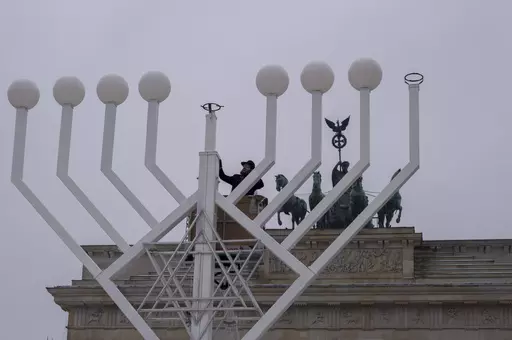 Rabbi Yehuda Teichtal, center, inspects a giant Hanukkah Menorah, set up by the Jewish Chabad Educational Center ahead of the Jewish Hanukkah holiday, in front of the Brandenburg Gate at the Pariser Platz in central Berlin, Germany, Wednesday, Dec. 6, 2023. Holocaust survivors from around the globe will mark the start of the fifth day of Hanukkah together with a virtual ceremony as worries grow among Jews worldwide about the Israel-Hamas war and a spike of antisemitism in Europe, the United Stat